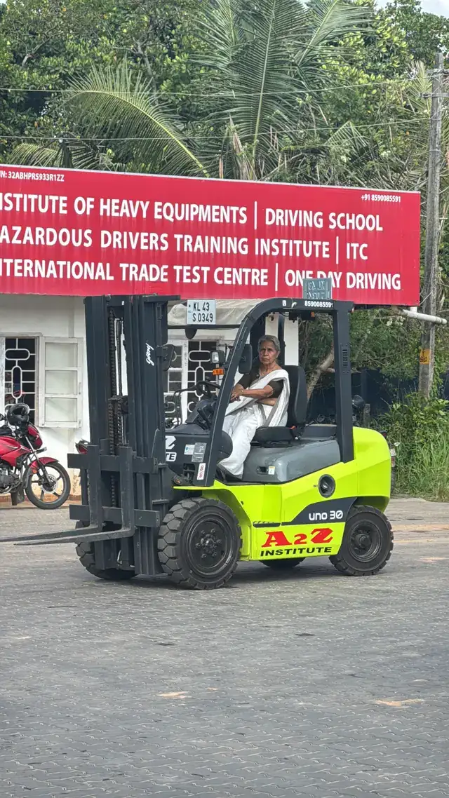 Radhamani Amma operating an A2Z Institute forklift in a white kasavu saree