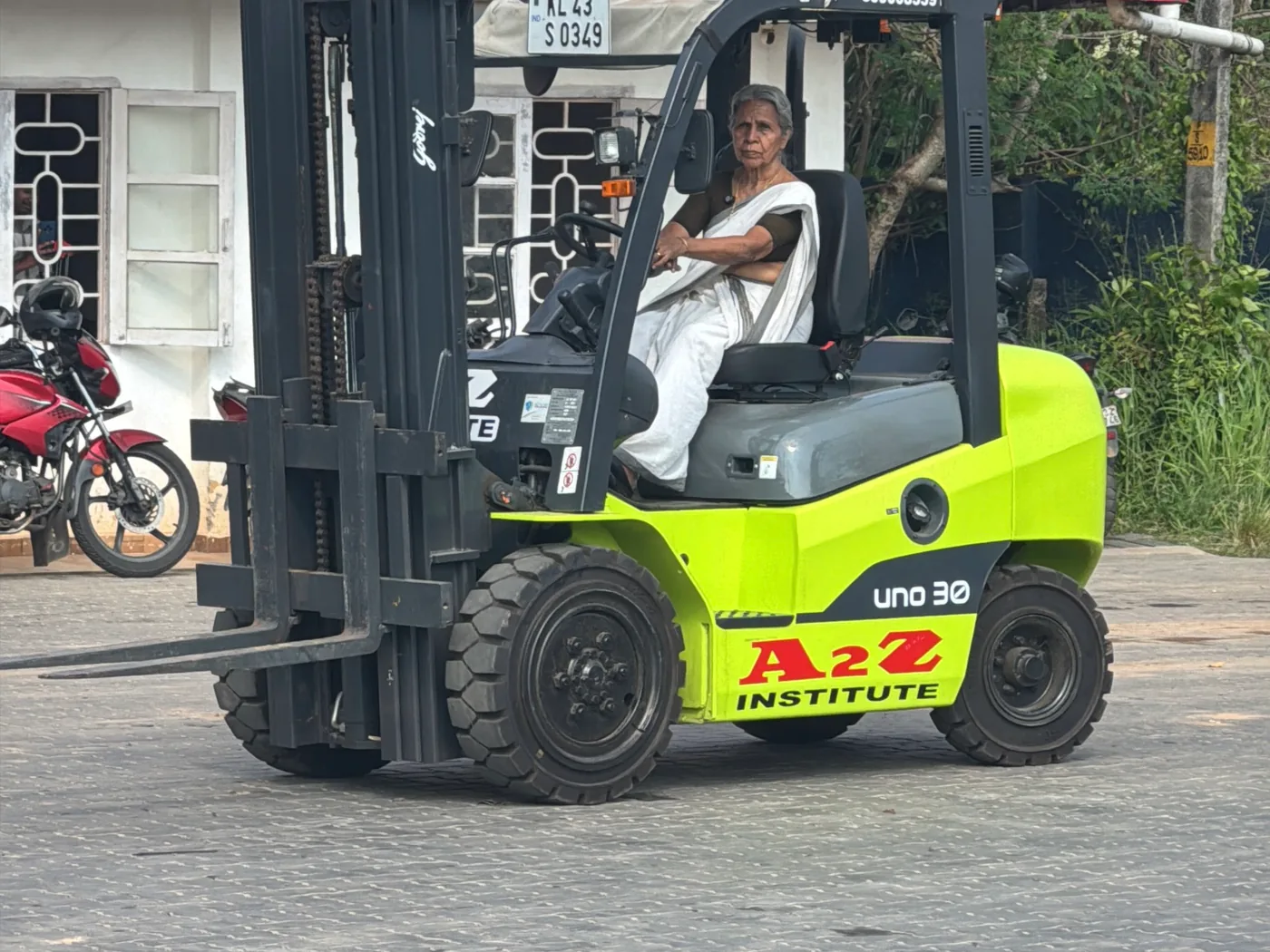 Radhamani Amma operating an A2Z Institute forklift in a white kasavu saree